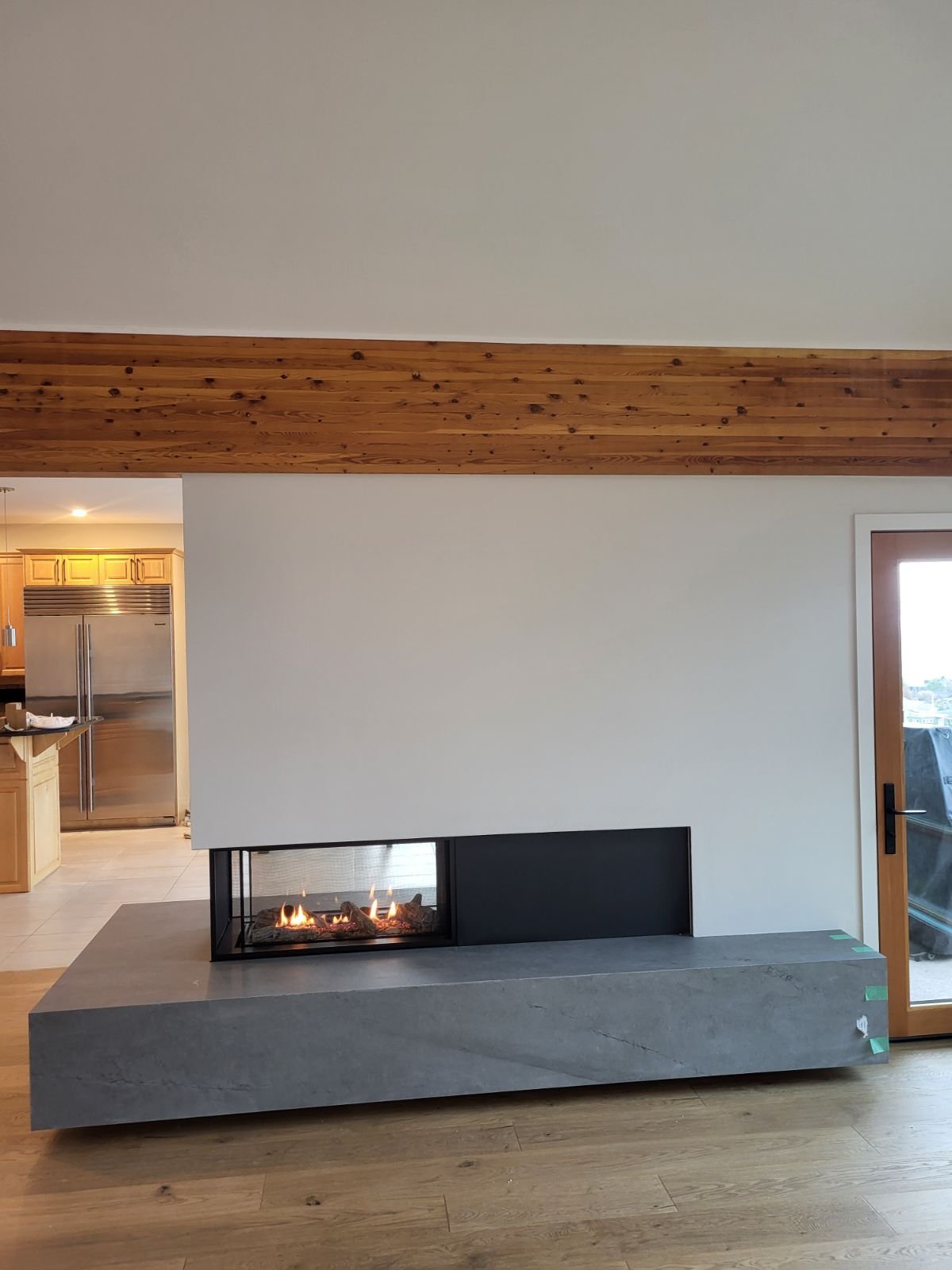 Two-sided floating gas fireplace with wood accent wall and mounted TV