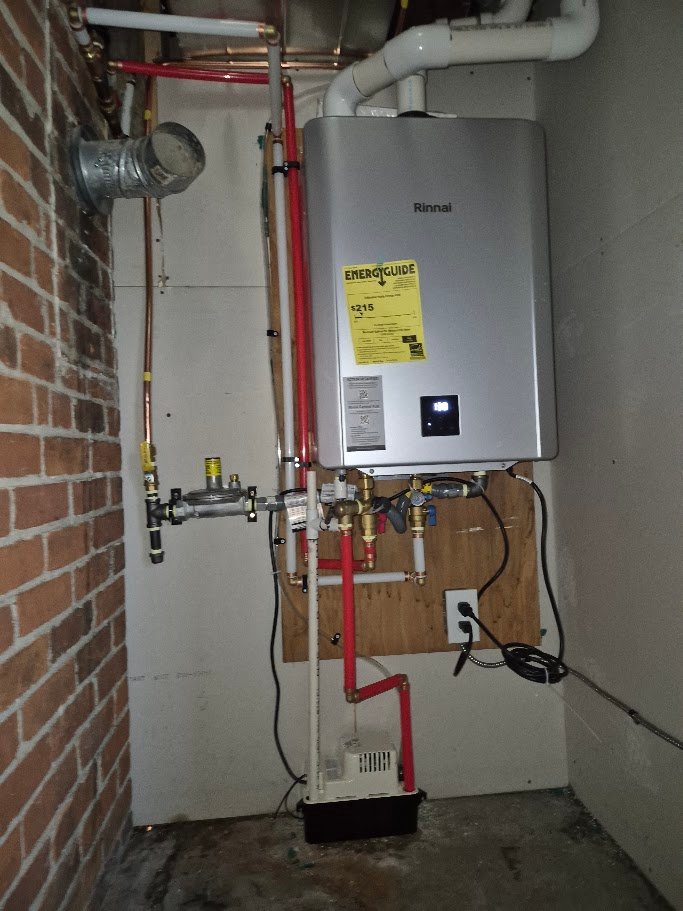 Tankless on-demand water heater installed on a mounting board with piping